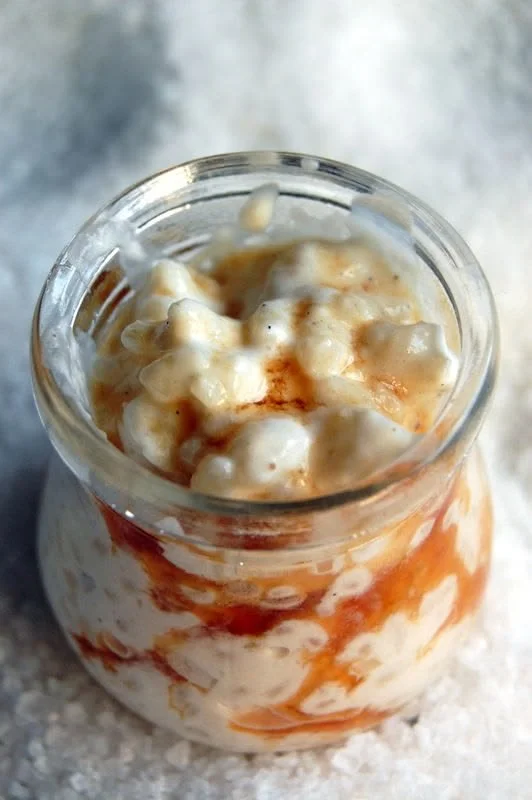 Riz au lait crémeux dans un bol, garni de caramel et d'amandes.