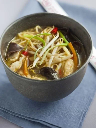 Soupe chinoise au poulet dans un bol avec des légumes frais